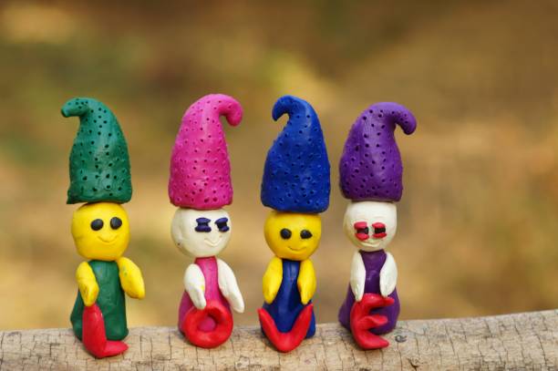 istock Four plasticine dwarfs stand in the forest on a colored background. 1284781878