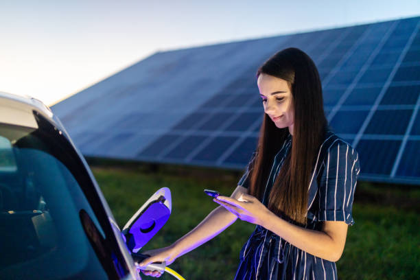 istock Woman using a phone and charging electric car 1284781907
