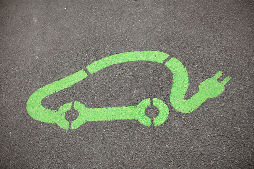 High angle view of a green electric car symbol drawn on the asphalt