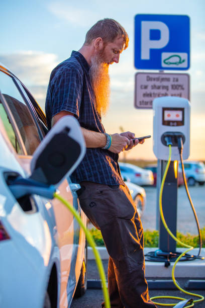 istock Man using phone and charging his electric car at the charging station 1284783166