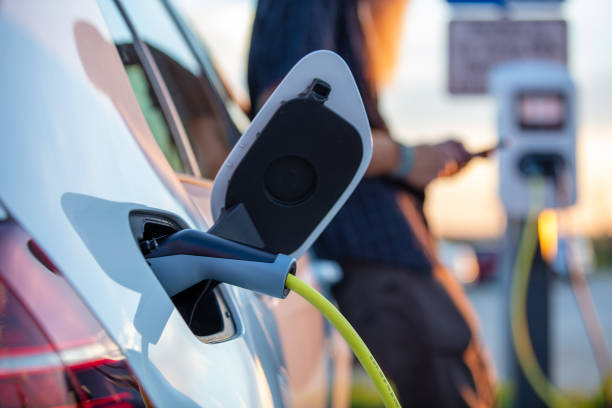 istock Man holding mobile phone and charging his electric car 1284783806