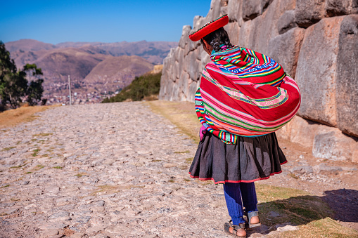 Peruvian woman wearing national clothing walking in Sacsayhuamán near Cuzco. The Sacred Valley of the Incas or Urubamba Valley is a valley in the Andes  of Peru, close to the Inca capital of Cusco and below the ancient sacred city of Machu Picchu. The valley is generally understood to include everything between Pisac  and Ollantaytambo, parallel to the Urubamba River, or Vilcanota River or Wilcamayu, as this Sacred river is called when passing through the valley. It is fed by numerous rivers which descend through adjoining valleys and gorges, and contains numerous archaeological remains and villages. The valley was appreciated by the Incas due to its special geographical and climatic qualities. It was one of the empire's main points for the extraction of natural wealth, and the best place for maize production in Peru.