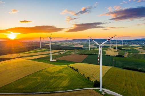 Aerial view of rural patchwork landscape with wind turbines at sunrise