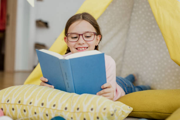 garota bonita está lendo um livro em casa no chão - child glasses elementary student reading - fotografias e filmes do acervo