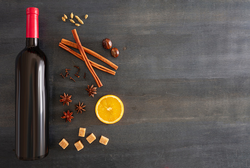 Mulled wine recipe ingredients, Christmas winter warming alcohol drink. Orange, cinnamon sticks, star anise, nutmeg, cloves and sugar on wooden table, top view, space