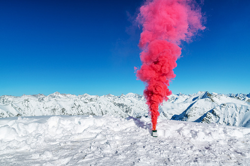 Smoke bomb with red smoke in the mountains