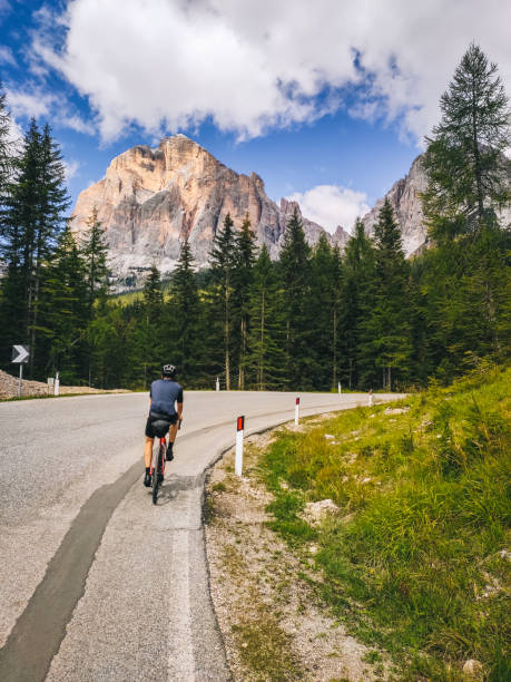 дорожный велосипедист едет вверх по горной дороге на солнце - country road fence road dolomites стоковые фото и изображения