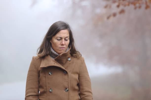 istock Sad middle age woman looking down in a forest in autumn 1284795232