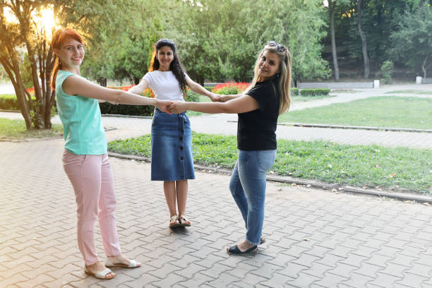 istock Three young smiling women friends holding hands and looking at the camera 1284795310