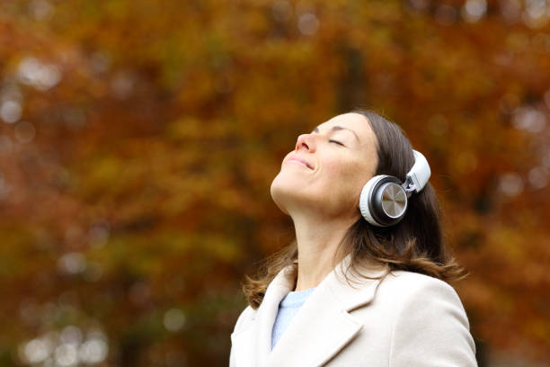 mujer de mediana edad respirando aire fresco con auriculares en otoño - mountain stream fotografías e imágenes de stock