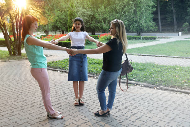 istock Three young smiling women friends hold hands in circle in the rays 1284795567