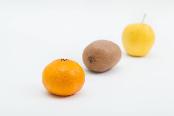 Orange tangerine and apple with whole kiwi on white