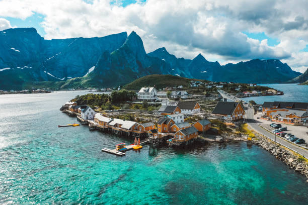 vista con droni di cabine di pesca gialle, montagne e oceano turchese a lofoten norvegia - fishing village nordic countries fjord foto e immagini stock