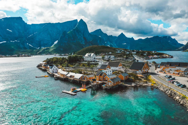 drone view of yellow fishing cabins, mountains and turquoise ocean in lofoten norway - fishing village imagens e fotografias de stock