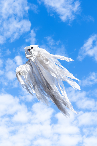 White flying ghost against blue sky for Halloween decoration