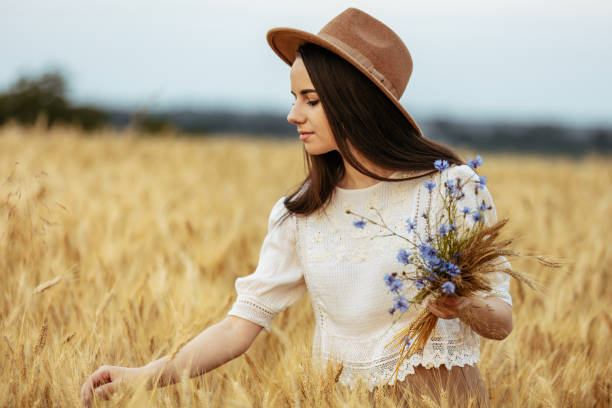 istock Woman with blue flowers in wheat field 1284800754