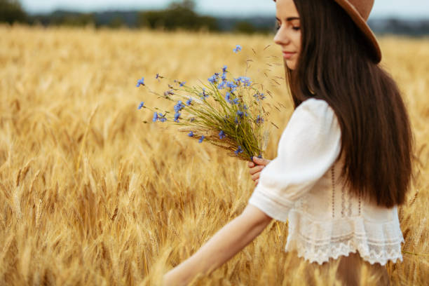 istock Woman holding blue flowers in wheat field 1284800882