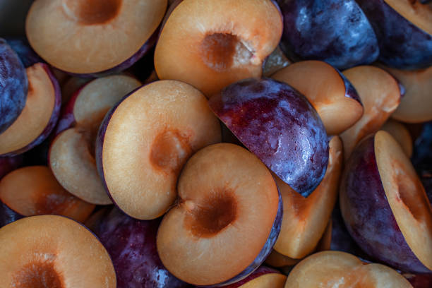 Food background of cutted halfs of blue plums. Top view with selective focus