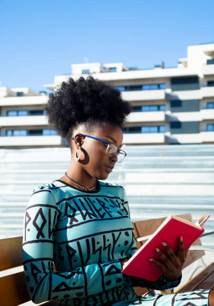 istock Young woman reading at book on street 1284802026
