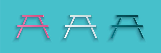 istock Paper cut Picnic table with benches on either side of the table icon isolated on blue background. Paper art style. Vector 1284802194