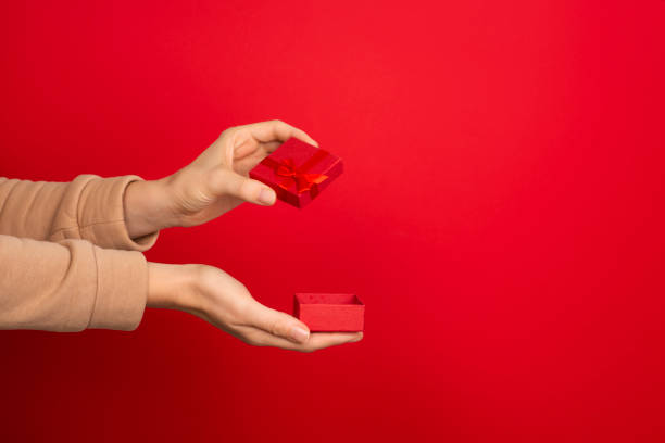 istock Female hand hold open red small jewelry box on red background. 1284804876