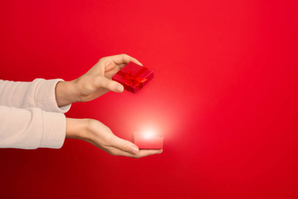 istock Female hand hold open red small jewelry box on red background. 1284804887
