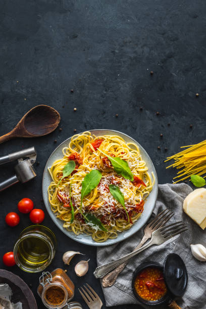 istock Italian dinner with pasta on ceramic plate with ingredients around on black background. Flat view. Top view. 1284806480