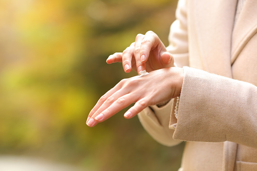 Woman hands in autumn applying moisturizer cream