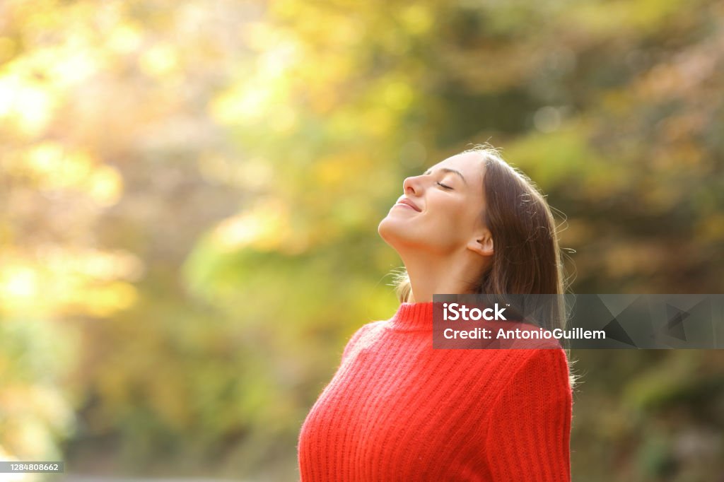 Woman in red breathing fresh air in autumn in a forest Women Stock Photo