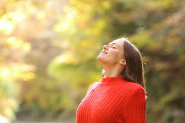 mulher em vermelho respirando ar fresco no outono em uma floresta - inhaling breathing exercise one person relaxation - fotografias e filmes do acervo