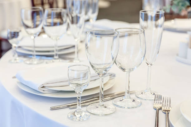 istock Fancy table set for dinner with napkin glasses in restaurant, luxury interior background. Wedding elegant banquet decoration and items for food arranged by catering service on white tablecloth table 1284811381