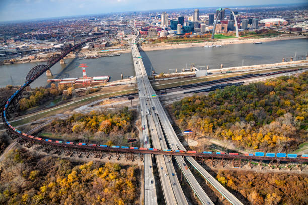 Freeway Into St. Louis A large interstate freeway and a freight train crossing paths on the Illinois side of the Mississippi River with the skyline of St. Louis, Missouri in the background. rail car stock pictures, royalty-free photos & images