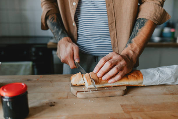 istock Anonymous Young Man Cutting Bread in the Kitchen - a Close Up 1284813473