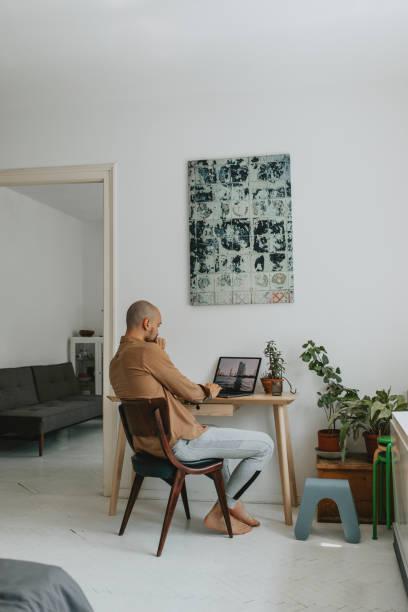 At the Home Office: Anonymous Young Man Working on his Laptop Computer at Home
