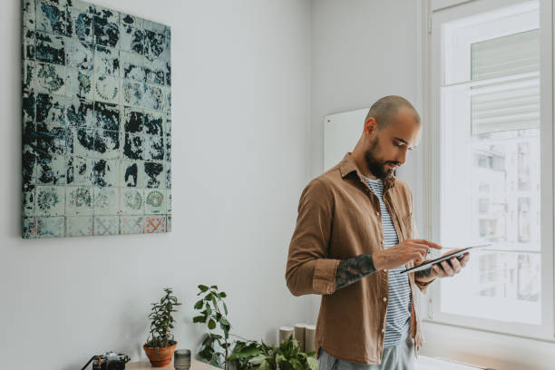 istock Casually Dressed Young Man Chatting with his Friends through a Tablet PC from his Living Room 1284813498