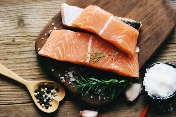 istock Raw salmon filet with herbs and spices on wooden background 1284817983