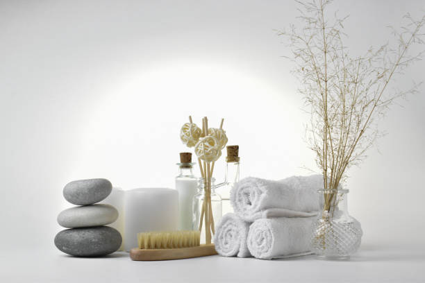 istock Composition with a candle and Spa stones and a natural brush for body massage on a light background. The concept of skin care. Bath accessories. 1284818366