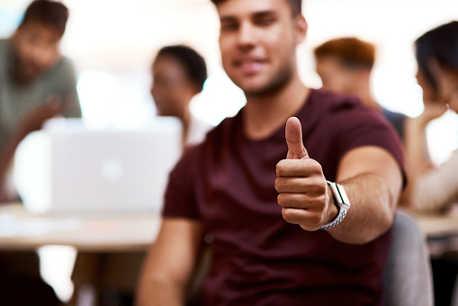 Closeup shot of a young businessman showing thumbs up in an office