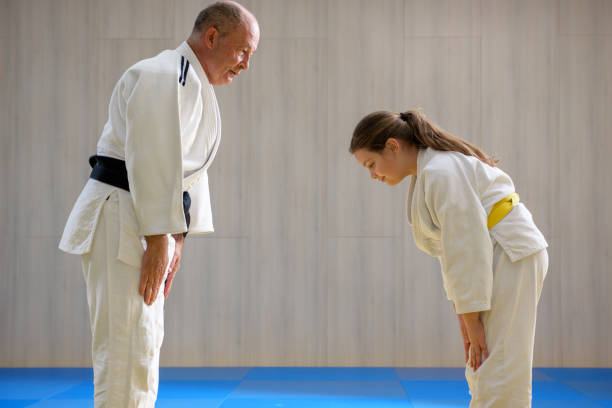 young female judo girl showing respect to old judo teacher - obi sash fotos imagens e fotografias de stock