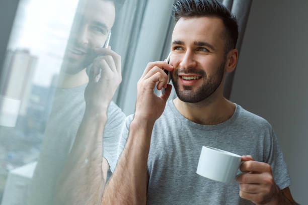 istock Bachelor man daily routine standing near the window single lifestyle concept drinking coffee phone call 1284822875