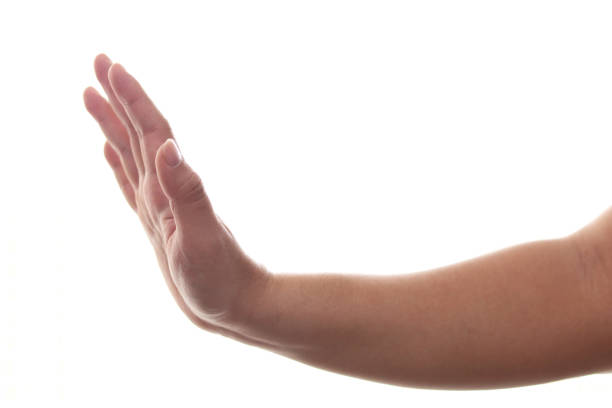 Two hands in front of white background. One is point to the other hand which is making stop gesture.