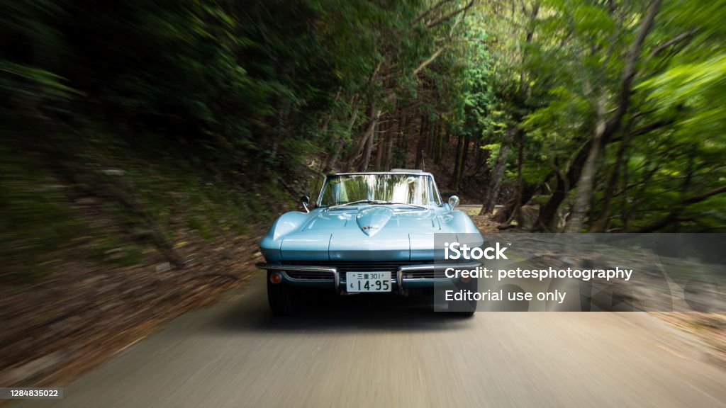 1964 Corvette Stingray on a forest drive Gozaisho mountain forest drive October/25/2020 a classic 1964 Corvette Stingray is driving along a narrow mountain forest road with blurred movement to show to speed of the vehicle. The Chevrolet Corvette is a classic American Muscle car that is still in production today. This one was imported to Japan which is quite rare especially for an old classic in such pristine condition. Chevrolet Corvette Stock Photo