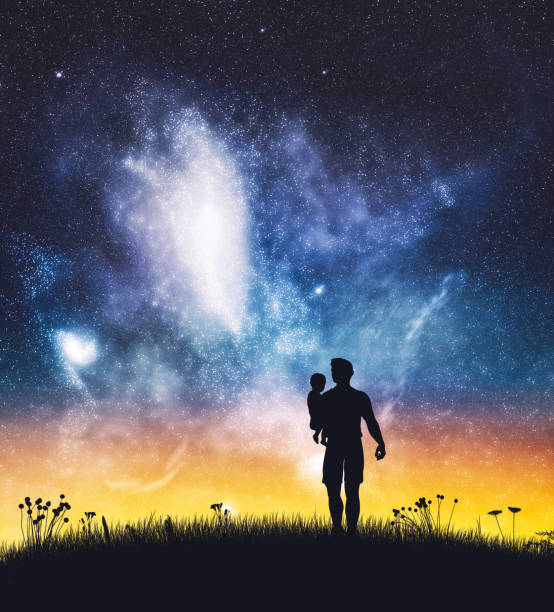 istock Father holding a baby on starry night sky. 1284835040