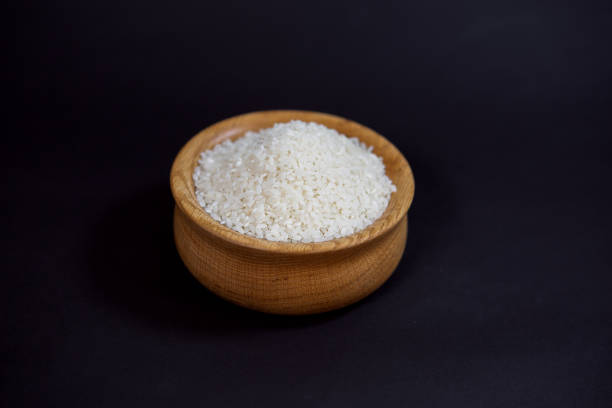 istock rice in a wooden bowl, isolated on a black background 1284835698