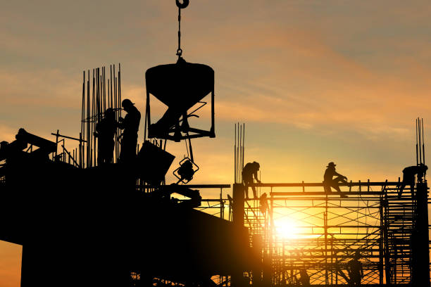 istock Silhouette of Engineer and worker checking project at building site background, construction site at sunset in evening time. 1284835861