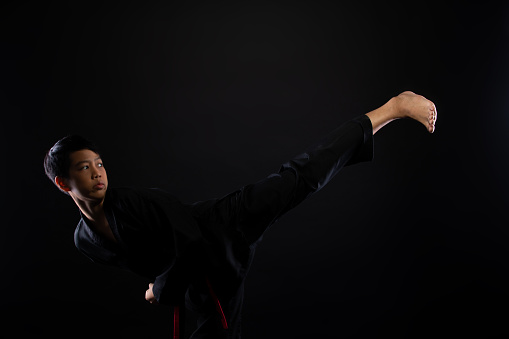 Master Red Black Belt TaeKwonDo Karate boy who is athlete young teenager show traditional Fighting poses in sport dress, black background isolated copy space