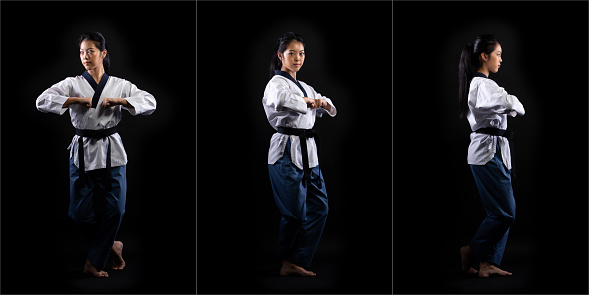 Master Black Belt TaeKwonDo Karate girl who is national athlete young teenager show traditional Fighting poses kick punch in sport uniform dress, black background isolated, motion blur on foots hands