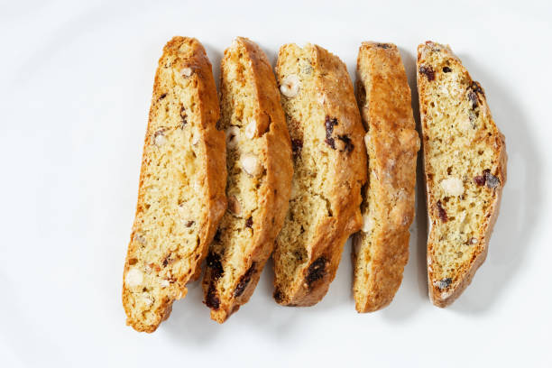 mehrere stücke italienische biscotti kekse auf schwarzem backblech. frisch gebackene kekse mit nüssen und getrockneten preiselbeeren. - biscotti stock-fotos und bilder