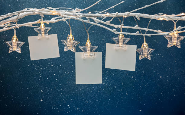 empty paper sheets hanging on bare twig with shaped star clothespins on dark blue background empty paper sheets hanging on bare twig with shaped star clothespins on dark blue background christmas card photos stock pictures, royalty-free photos & images
