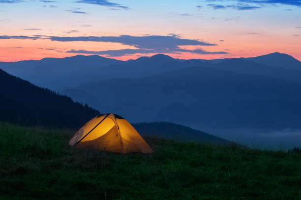 istock Orange tourist tent illuminated from inside on mountain 1284844156